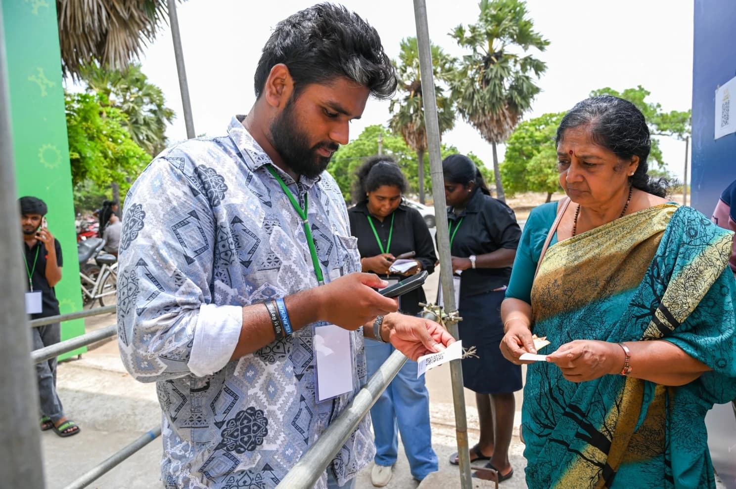 A gate volunteer scans a visitor’s printed QR ticket at the entrance